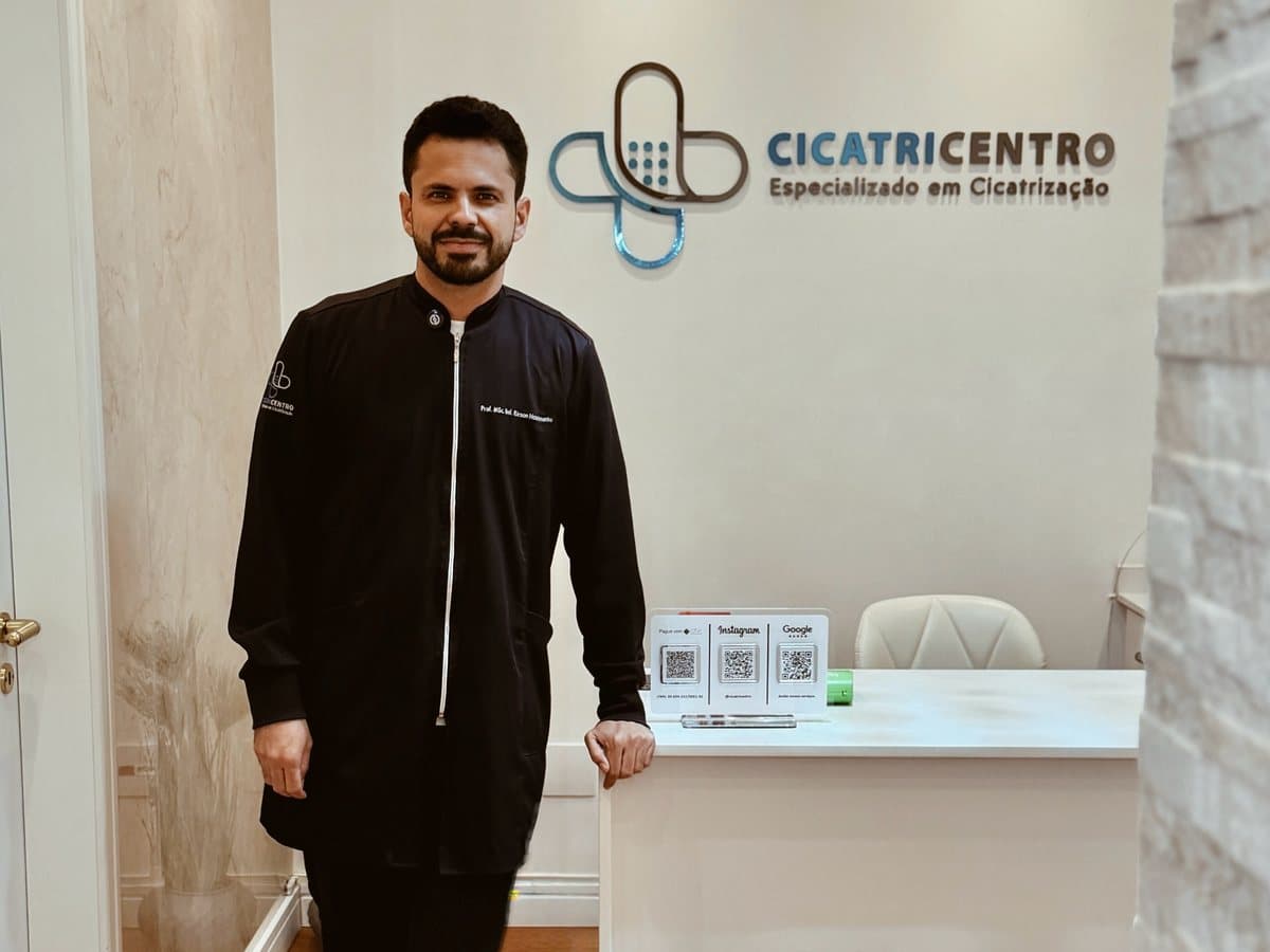 Profissional na recepção da Cicatricentro, ao lado do logotipo da clínica