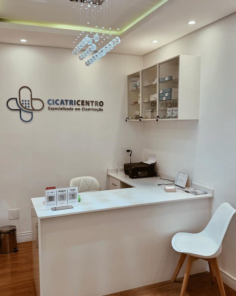 Recepção da Cicatricentro, com balcão branco e o logotipo da clínica na parede